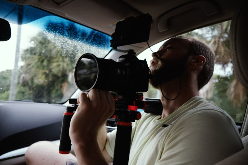 a man in a car recording with big lens camera | car videos